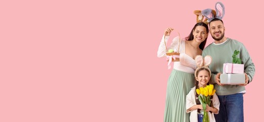 Happy family in bunny ears, with Easter basket, flowers and gifts on pink background with space for text