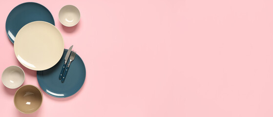 Different clean plates with silver cutlery on pink background