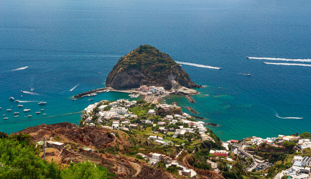 Veduta della torre di sant'Angelo dal belvedere. Panorama mediterraneo con isolotto, istmo, borgo, case colorate, spiaggia, mare, barche, scie. Sant'Angelo d'Ischia. Isola d'Ischia in estate. Italia