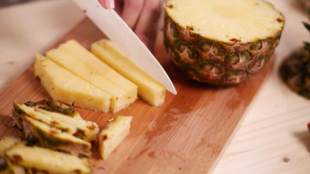 Close up of woman's hands chopping fresh ananas for fuits salad