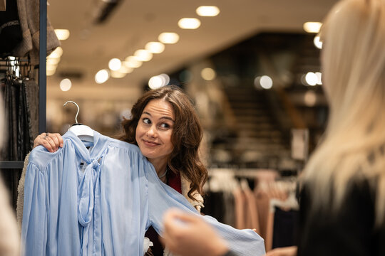 Woman making funny face deciding on buying blouse