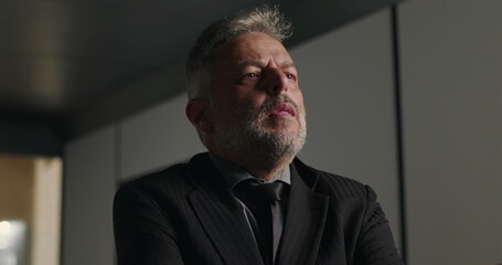 Obraz premium Pensive businessman lost in thought during corporate meeting with hand on chin and intense gaze in professional boardroom setting