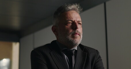 Pensive businessman lost in thought during corporate meeting with hand on chin and intense gaze in professional boardroom setting