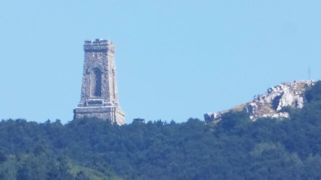 A handheld video with over 120&times; combined zoom shows the Shipka Freedom Monument on Shipka Peak in the Balkan Mountains, viewed from Koprinka Reservoir during a hot summer day, Bulgaria, 30 Aug. 2019