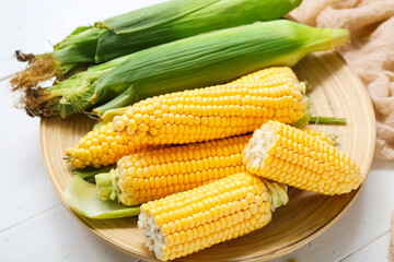 Plate with fresh corn cobs on white wooden table, closeup