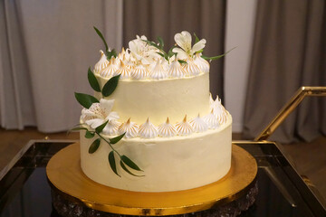 Wedding cake, a cream cake decorated with cream and flowers on a gold tray.