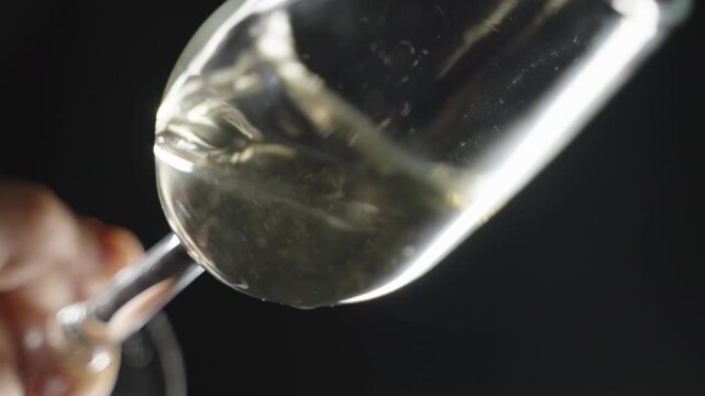 moving a glass of chamomile wine on a black background