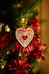 A handcrafted gingerbread ornament hangs on a Christmas tree, illuminated by a warm festive glow. A cozy, high-quality commercial holiday image perfect for seasonal designs and advertising.