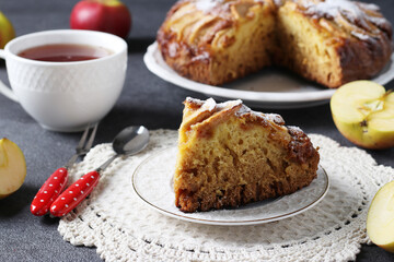 Homemade apples pie Charlotte with cut piece and cup of tea on gray background