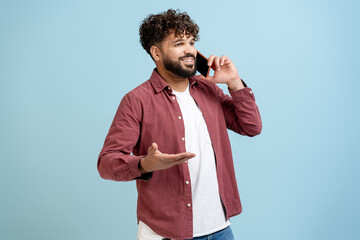 Young man talking on smartphone, communicating, smiling, making gesture