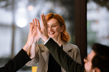 Team members celebrating a successful project with a high five in a modern office setting during afternoon hours