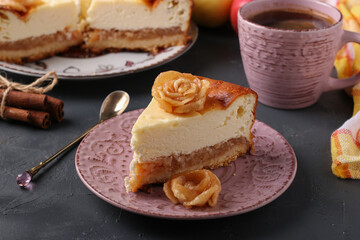 Cheesecake with apples decorated with roses from apples on plate on gray background and cup of coffee
