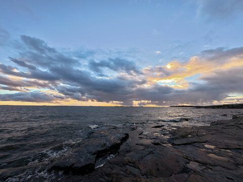 sunset over rocky shoreline featuring moody clouds and shimmering tide pools