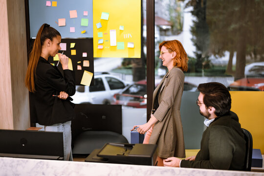 Team members interact in a bright office space with colorful notes and casual atmosphere during a collaborative brainstorming session on a workday