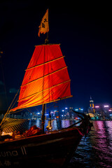 Awesome nighttime view of a brightly illuminated junk boat in Victoria Harbor in front of Hong Kong's fantastic skyline with its impressive skyscrapers