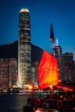 Awesome nighttime view of a brightly illuminated junk boat in Victoria Harbor in front of Hong Kong's fantastic skyline with its impressive skyscrapers