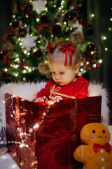 Little girl sitting in a gift box at Christmas day