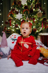 Little girl sitting near Christmas tree at the holiday