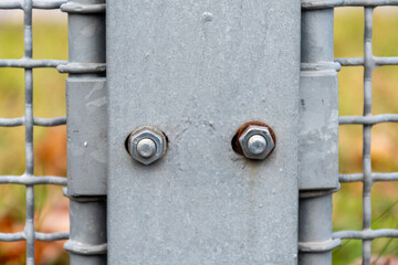 Metal bolts on a galvanized fence post with rust elements and engineering design details