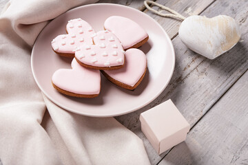 Plate with tasty heart shaped cookies, decor and gift box on grey wooden background. Valentine's Day celebration