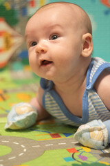 Newborn Baby lying on stomach in scratch mittens. Protect hands from accidental scratches. Babycare and safety