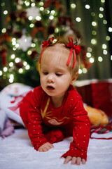 Little girl sitting near Christmas tree at the holiday