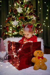 Little girl sitting in a gift box at Christmas day