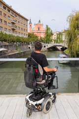 Man tourist with a disability enjoys Europe Ljubljana scenery from the Ljubljanica bridge