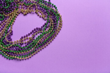 Colorful beads for Mardi Gras celebration on purple background