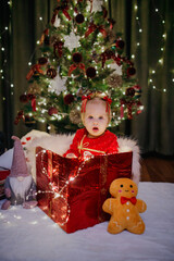 Little girl sitting in a gift box at Christmas day