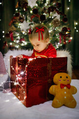 Little girl sitting in a gift box at Christmas day