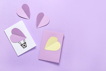 Beautiful greeting cards and paper hearts on lilac background. Valentine's Day celebration