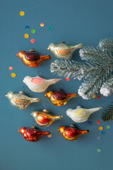 Old vintage Soviet Christmas ornaments birds with tree branch, top view on blue background, selective focus