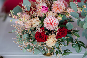 Coziness and style. Modern event design. Table setting at wedding reception. Floral compositions with beautiful flowers and greenery, candles, laying and plates on decorated table.