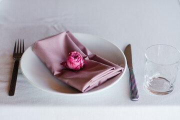 Coziness and style. Modern event design. Table setting at wedding reception. Floral compositions with beautiful flowers and greenery, candles, laying and plates on decorated table.