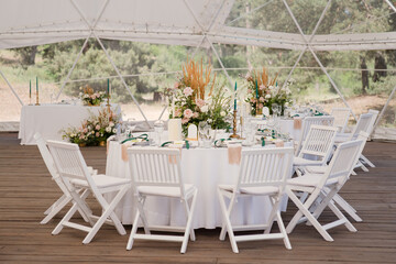 Coziness and style. Modern event design. Table setting at wedding reception. Floral compositions...