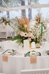 Coziness and style. Modern event design. Table setting at wedding reception. Floral compositions...