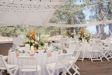 Coziness and style. Modern event design. Table setting at wedding reception. Floral compositions...