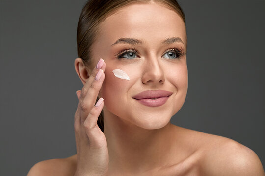 Beautiful woman applying facial lotion for smooth skin in a skincare routine at home while enjoying self-care time