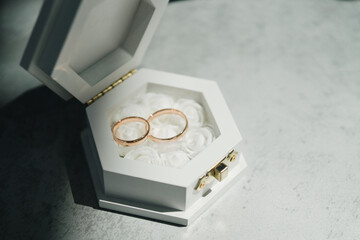 Modern wedding jewelry. Closeup of two wedding rings in a vintage box with flower petals.