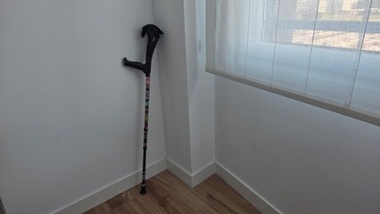 Mobility aid crutch in a minimalist corner interior setting
