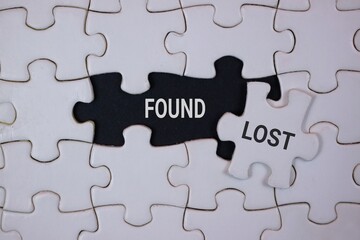Fototapeta premium A jigsaw puzzle shows a black 'FOUND' piece adjacent to a white 'LOST' piece, symbolizing missing links, belonging, and the quest for balance in personal and professional life.
