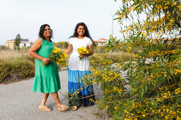 Mother and daughter smiling holding yellow flowers outdoors