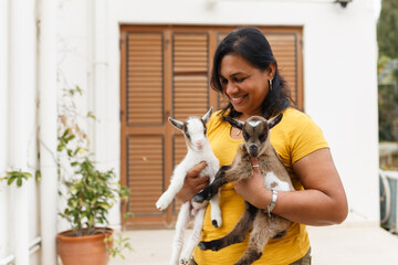 Smiling woman holding two cute baby goats