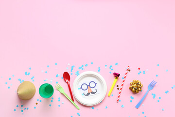 Table setting with festive postcard, confetti and party decor for April Fools Day on pink background