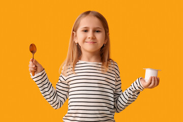 Cute little girl with spoon and yogurt on yellow background