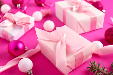 Gift boxes with Christmas balls on pink background