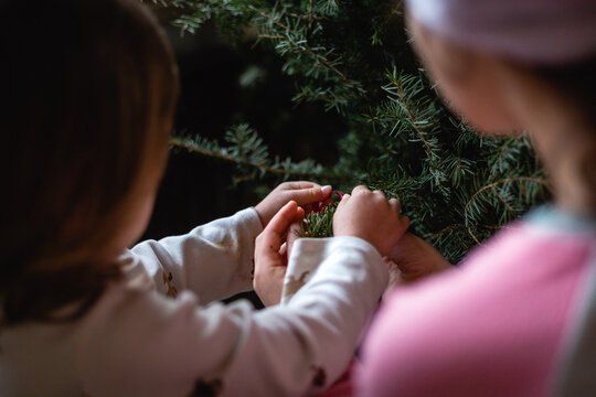rear view of two children decorating christmas tree together at home