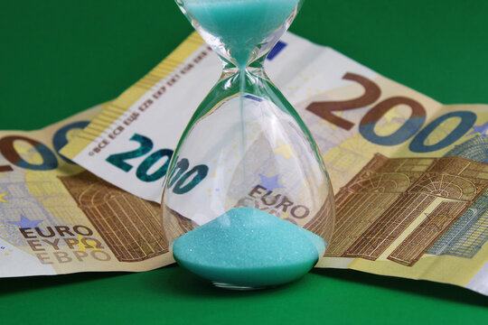 Time is money, hourglass next to two hundred euro banknotes