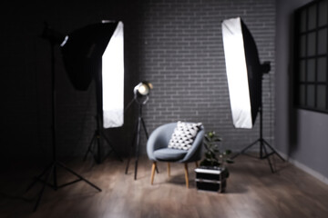 Interior of dark photo studio with professional equipment and armchair